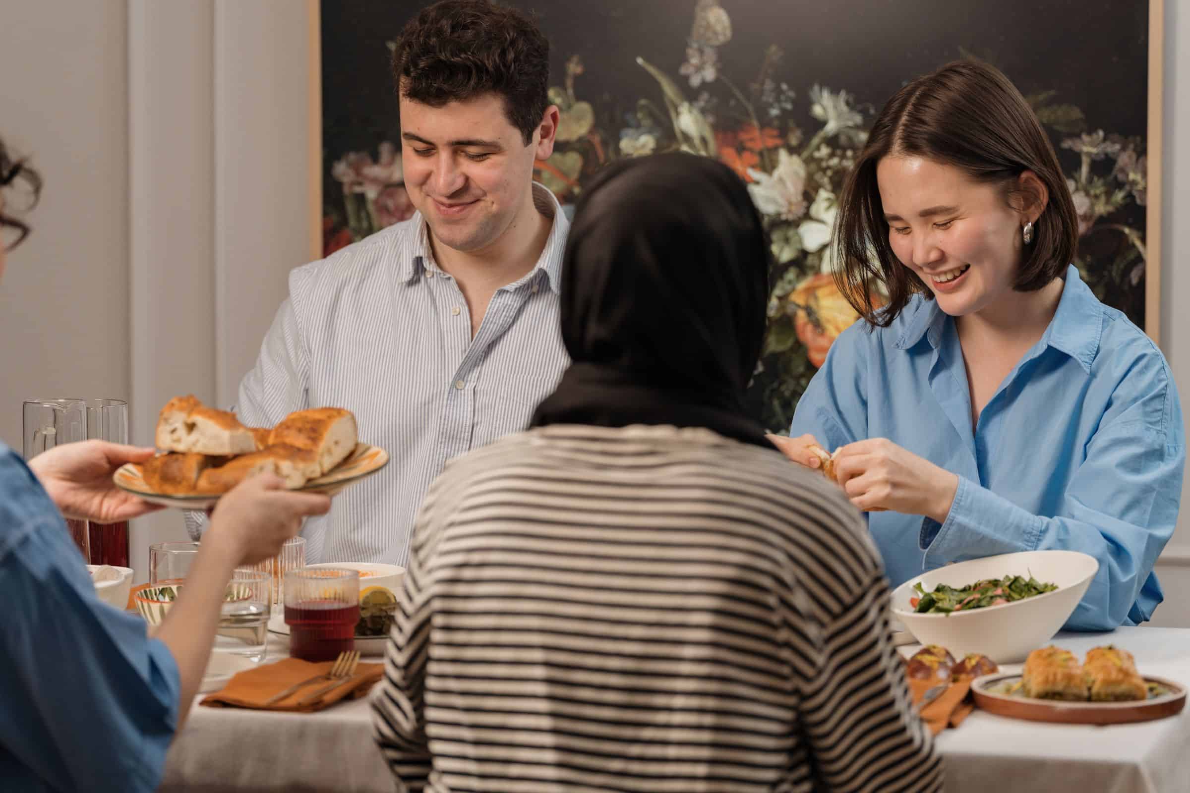 Friends passing bread and salad around a table at a shared meal