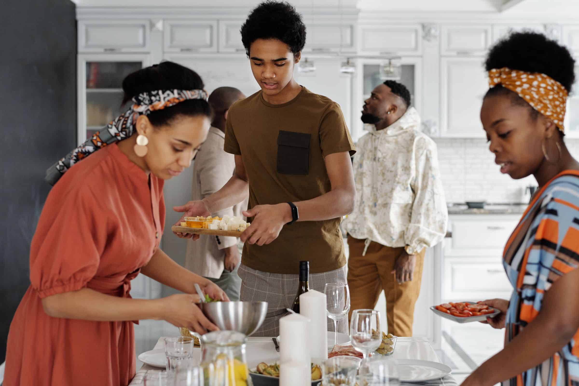 Friends setting the table and plating food together before dinner